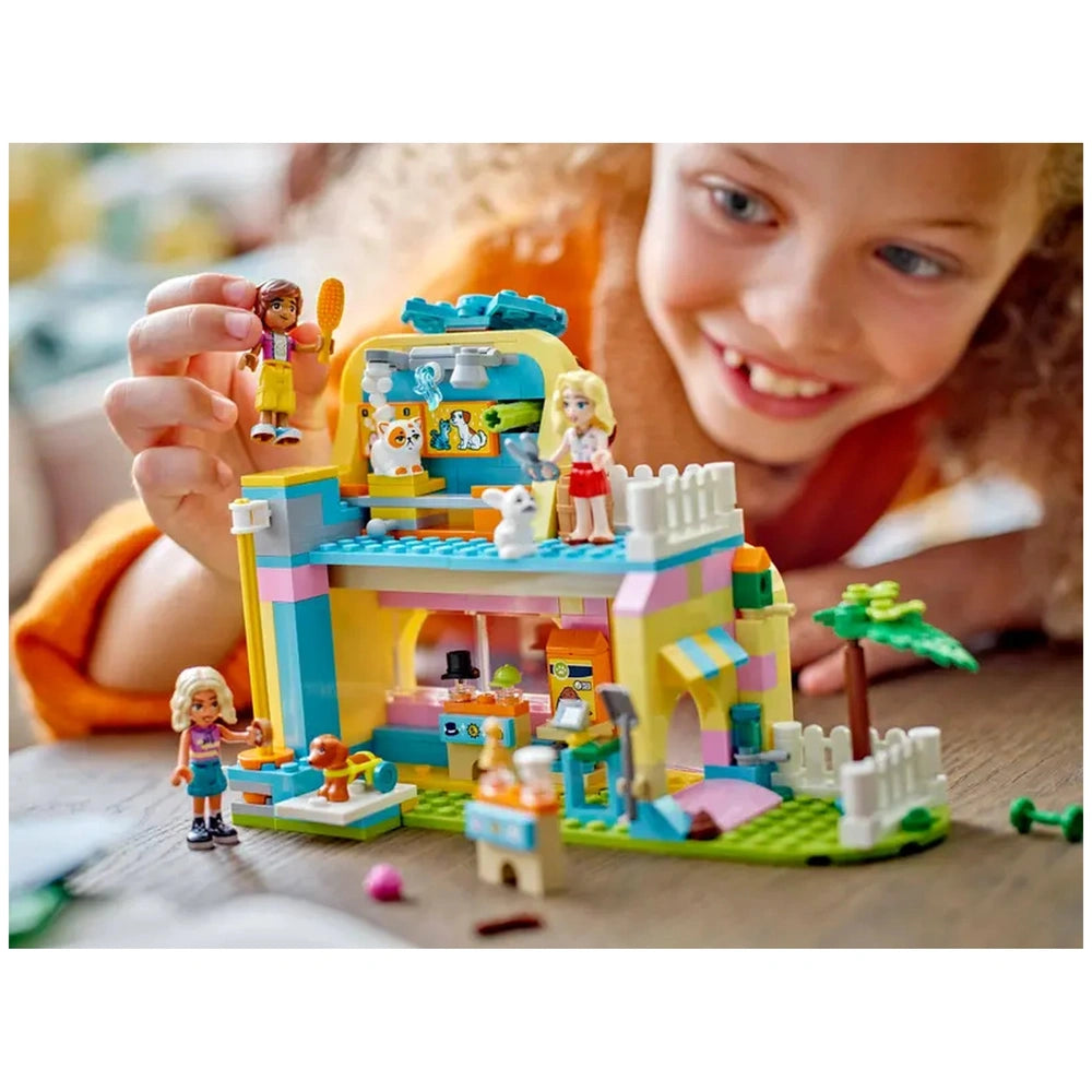 A smiling child plays with the colorful LEGO® Friends Pet Accessories Shop set, featuring minidolls and cute pet figures.