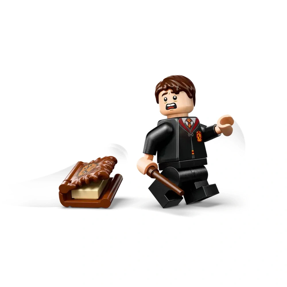 A LEGO figure of a young wizard in a Hogwarts uniform, looking surprised while holding a wand, stands beside a brick-built, furry Monster Book of Monsters.