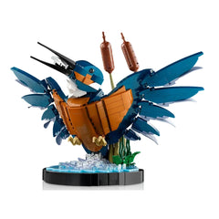 A vibrant LEGO® model of a kingfisher bird, with striking blue and orange plumage, perched amidst buildable reeds, over a stylized water setting.