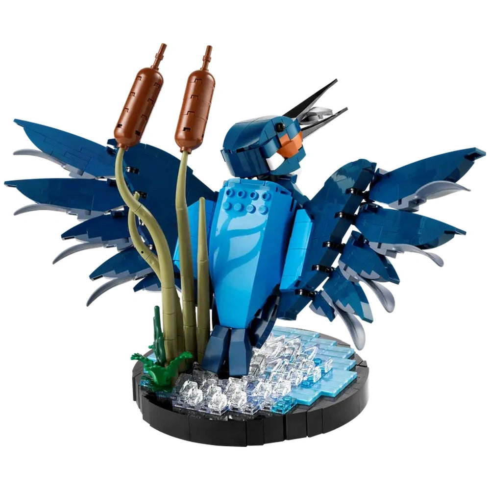 LEGO® Icons Kingfisher Bird set, showcasing a detailed blue bird with vibrant plumage, perched amidst green reeds on a shimmering water surface.