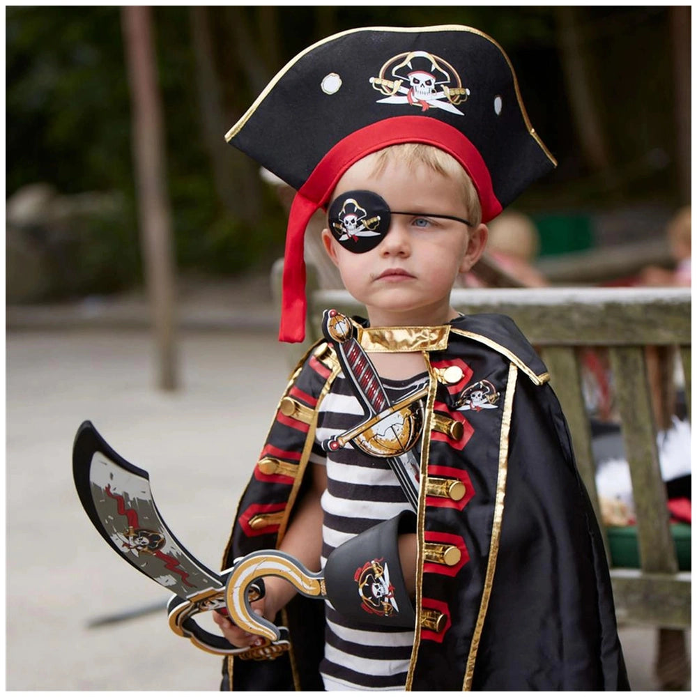 Young child dressed in a pirate costume with a red-banded hat, black flag, gold-trimmed cape, and holding a sword.