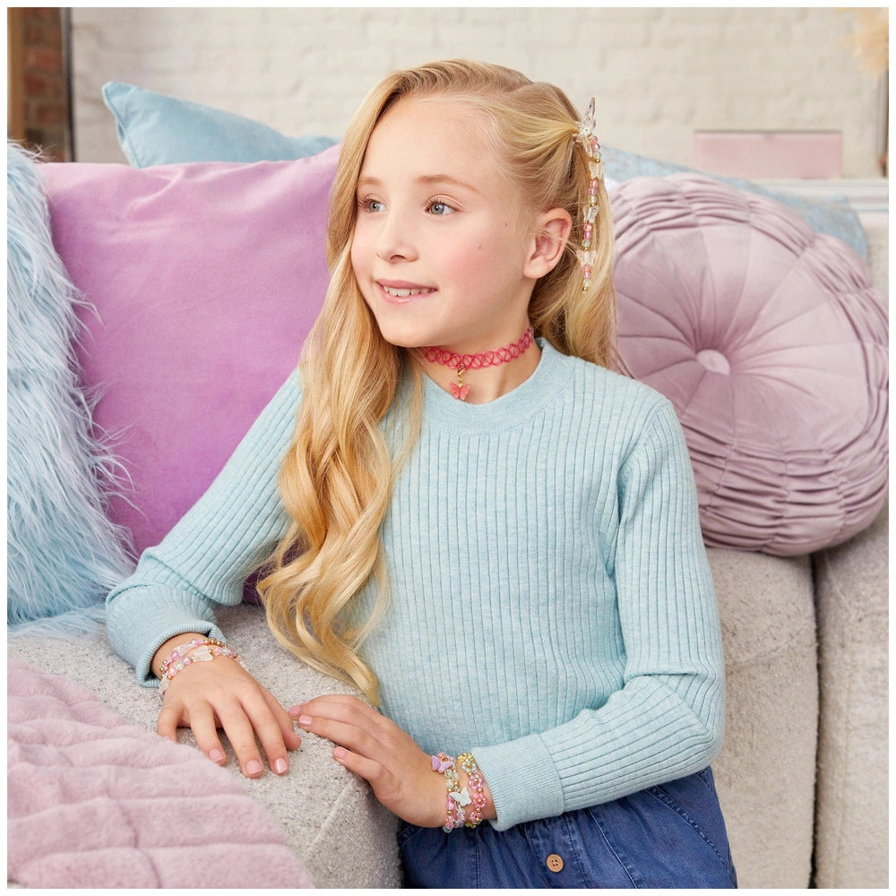 Butterfly Jewelry Set worn by a smiling girl in a light blue sweater, sitting on a light blue couch with a purple pillow.