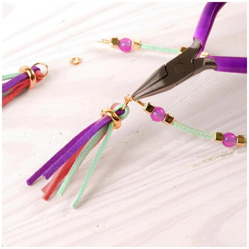 Gold link suede bracelets with pink and green beads on white string, cut with purple-handled scissors.