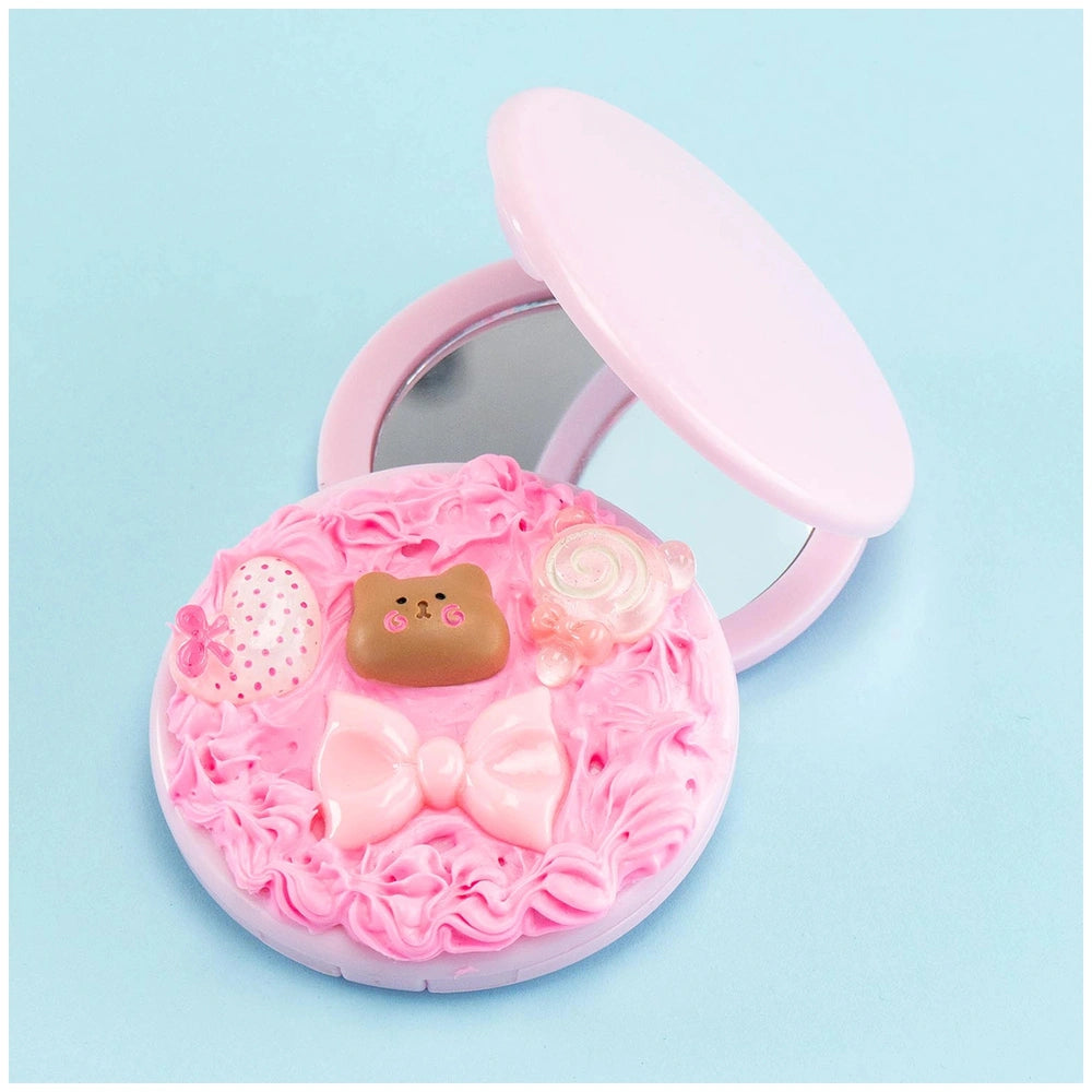 Momomi Decoden Kawaii creamy mirror and brush features a pink container with a bear, bow, egg, rose, and heart decorations.