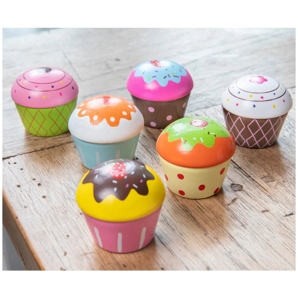 Cupcake assortment in gift box featuring pink, orange, brown, and yellow cupcakes with various icing and sprinkles.