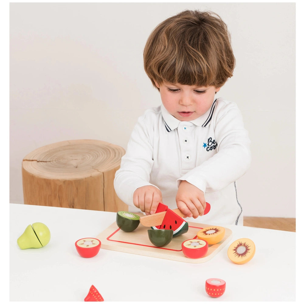 New Classic Toys cutting set features children playing with plastic fruits and vegetables on a wooden table, enhancing role p