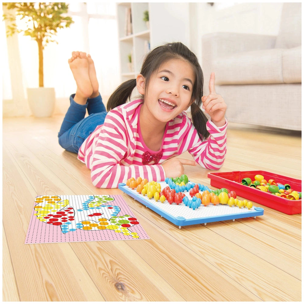 Young girl in pink and white striped shirt and blue jeans playing with Quercetti FantaColor Tab on a wooden floor in a white 