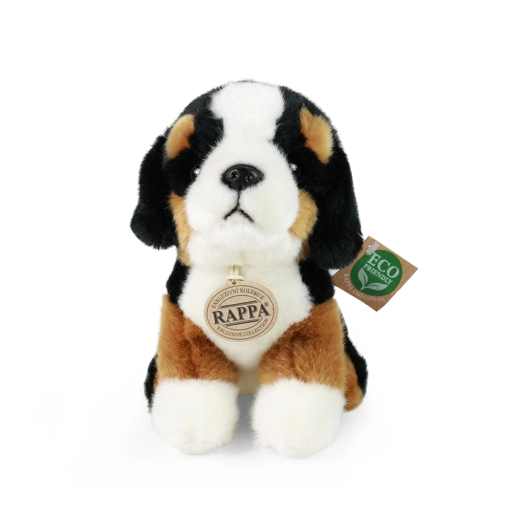 Plush mountain dog toy with black and white markings, floppy ears, and eco-friendly tag against a plain white background.