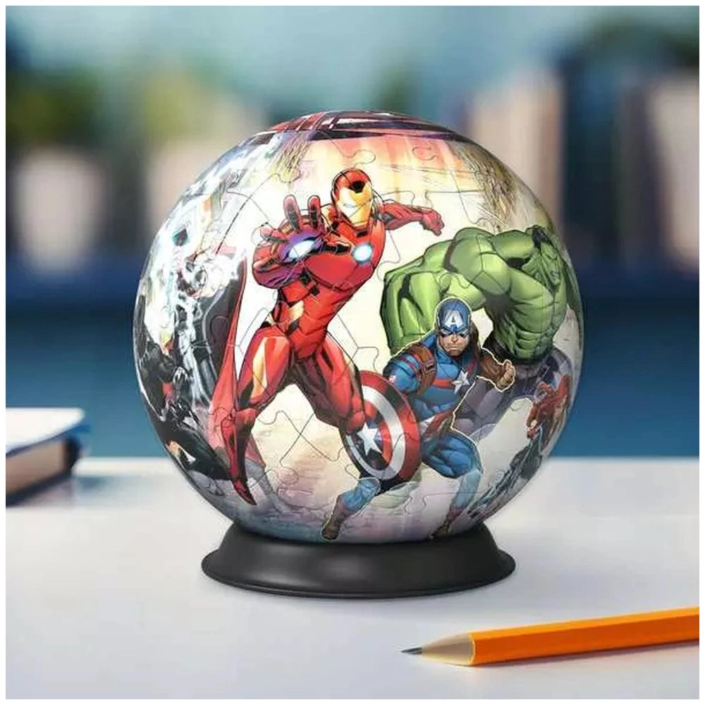 3D puzzle ball featuring vibrant superhero illustrations in action poses, resting on a black base with a pencil nearby.