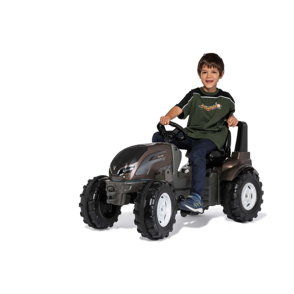 ROLLEY TOYS rollyFarmtrac Premium II Valtra is a brown and black riding toy with a smiling boy seated and steering.