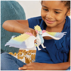 Rainbow Dragon toy figurine with colorful accents, held by a smiling child in a blue shirt, indoors.