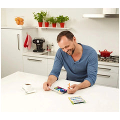 Smart Games - IQ Fit logic puzzles are displayed on a modern kitchen counter while a smiling man engages with them.