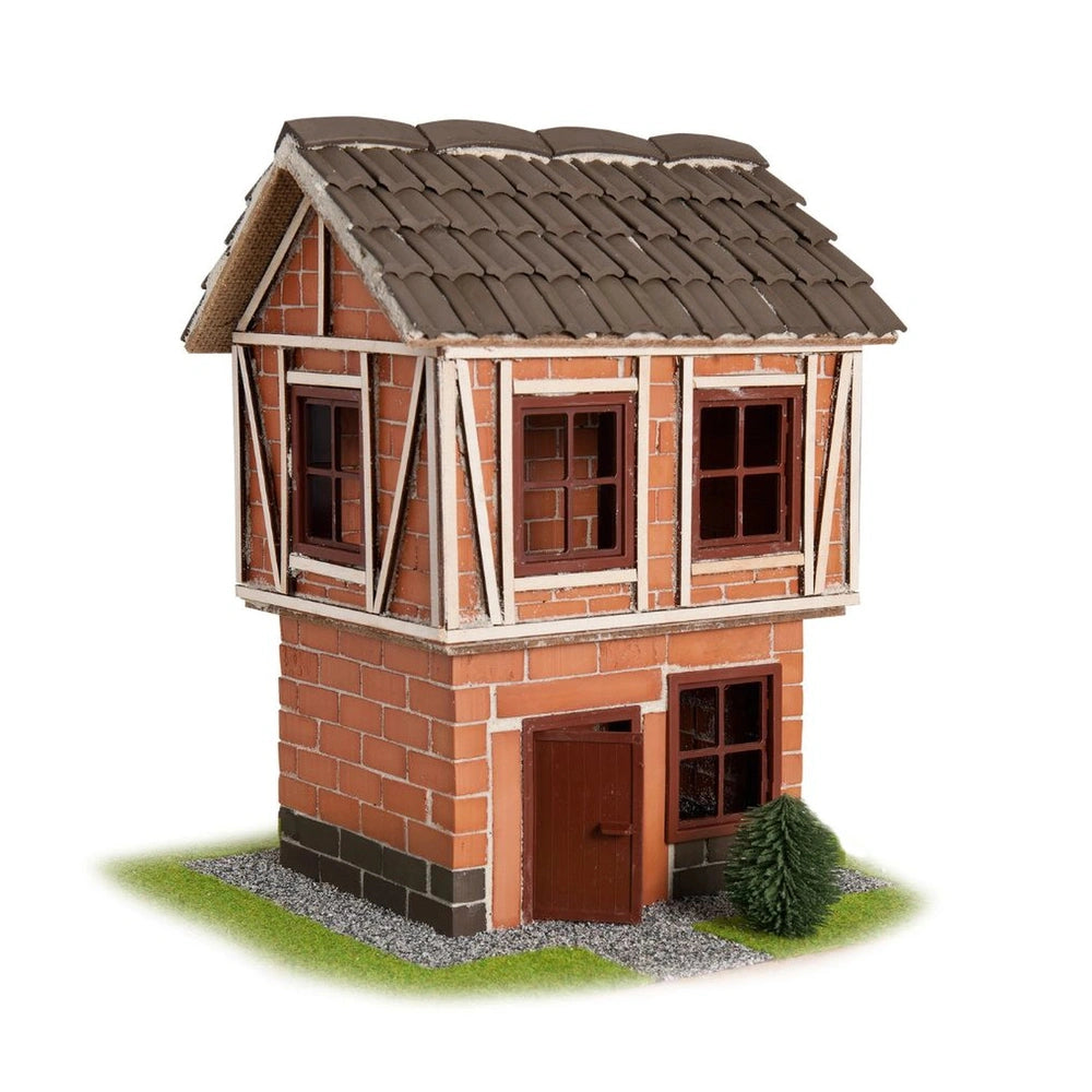 Teifoc's model-sized timber-framed house features a brick exterior, pitched shingle roof, and a grassy base with a gravel pat