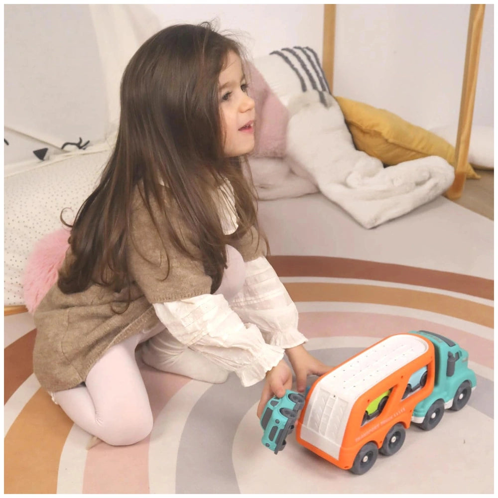 Baby Challenge Sustainable Car Transporter Set is being played with by a young girl on a colorful patterned floor.