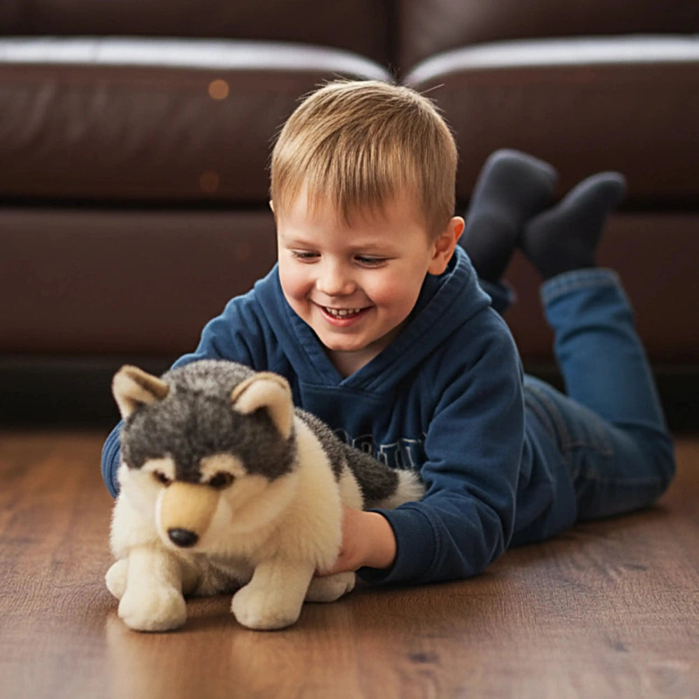 Wolf 25 cm plush toy with gray and white fur pattern beside a smiling child in a blue hoodie on a wooden floor.